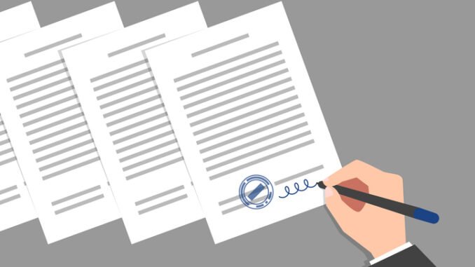 Stack of documents and hand of person wearing business suit, signing and stamping them. Concept of signing of new acts, decrees, agreements, political, legal or business relationships
